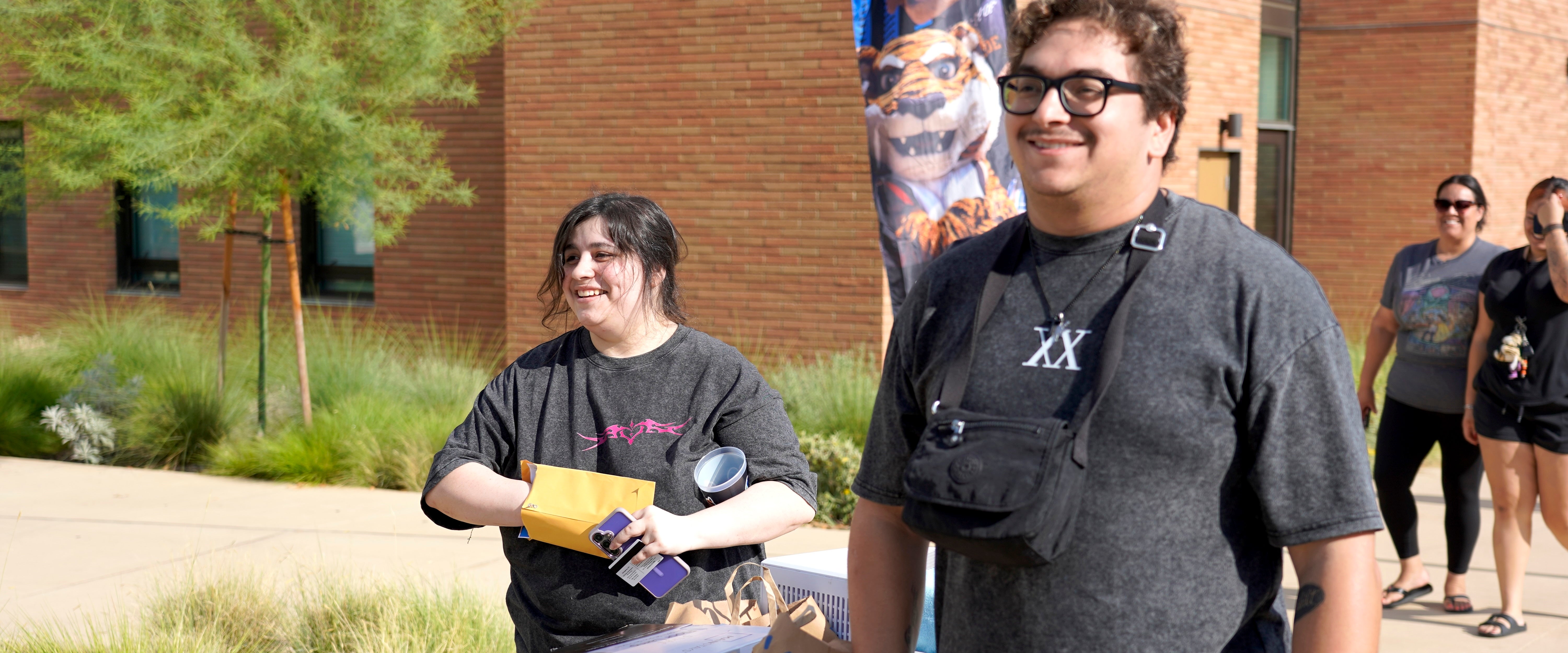 Two students push a blue move-in cart.