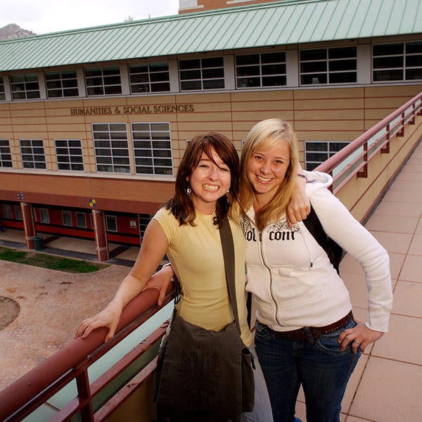 Students smiling at Humanities & Social Sciences building